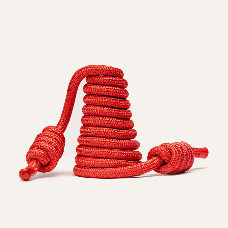 A bright red coiled rope with two knotted ends, displayed on a clean white studio background.