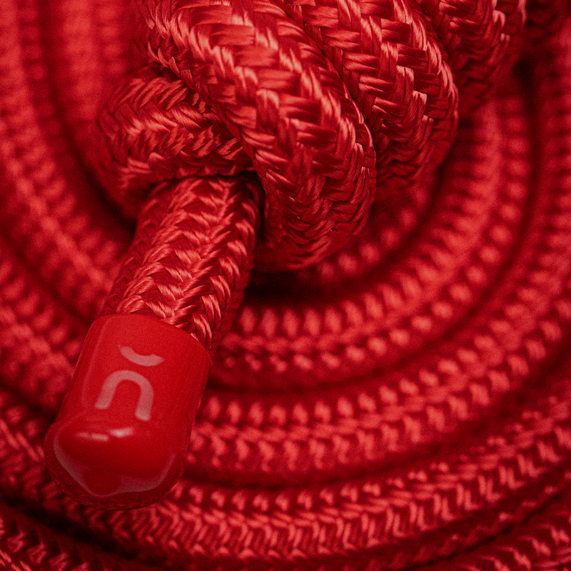 Close-up of a red rope flow hono with a knot and a red rope clip featuring a logo.