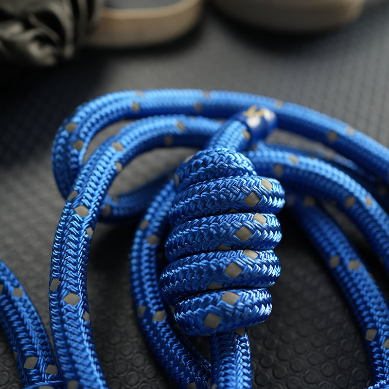 A close-up of a bright blue braided rope with small reflective diamond-shaped accents, coiled on a dark textured surface.